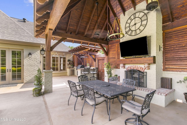 view of patio featuring an outdoor brick fireplace, a gazebo, french doors, and exterior kitchen