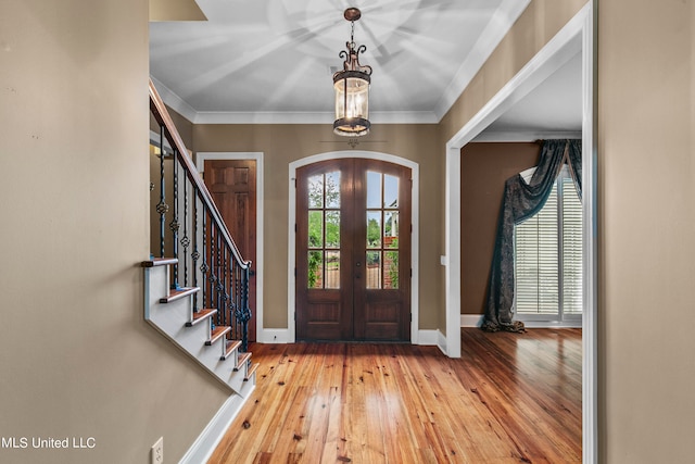 entrance foyer with french doors, crown molding, and light wood-type flooring