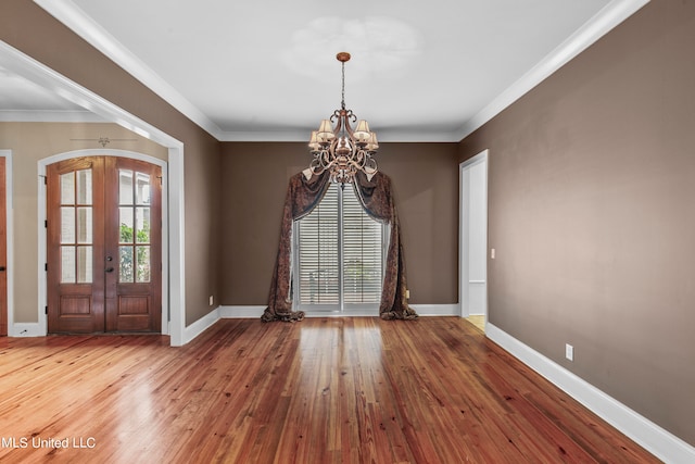 interior space with an inviting chandelier, french doors, wood-type flooring, and crown molding