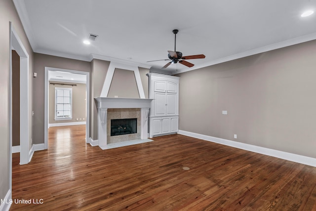 unfurnished living room featuring crown molding, a tiled fireplace, wood-type flooring, and ceiling fan