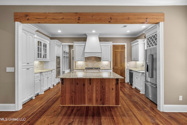 kitchen featuring a kitchen island, white cabinetry, stainless steel appliances, custom range hood, and dark wood-type flooring