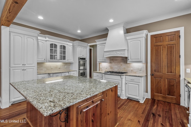 kitchen featuring premium range hood, white cabinets, and a kitchen island