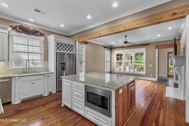 kitchen featuring built in appliances, a center island, white cabinetry, light stone counters, and dark hardwood / wood-style flooring