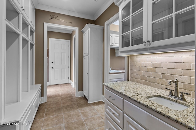 interior space with vanity, tasteful backsplash, ornamental molding, and tile patterned flooring