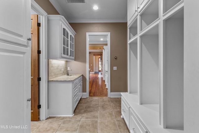 mudroom with light tile patterned floors, ornamental molding, and sink