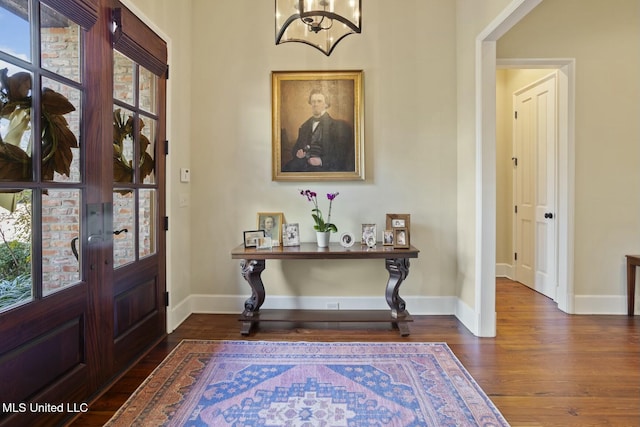 entrance foyer featuring an inviting chandelier, plenty of natural light, and dark hardwood / wood-style floors