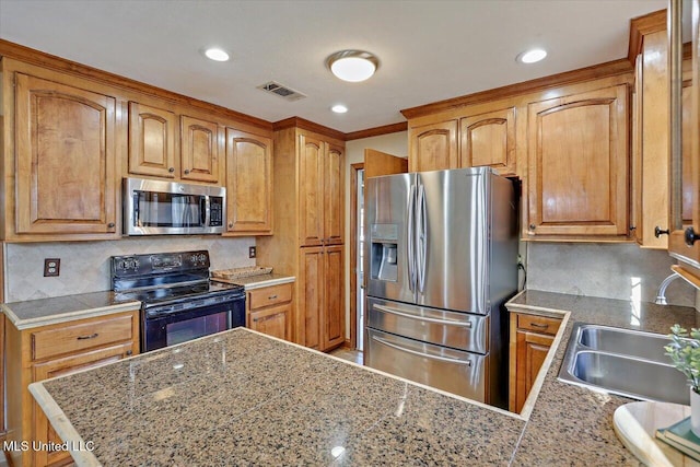 kitchen featuring stainless steel appliances, visible vents, backsplash, brown cabinetry, and a sink