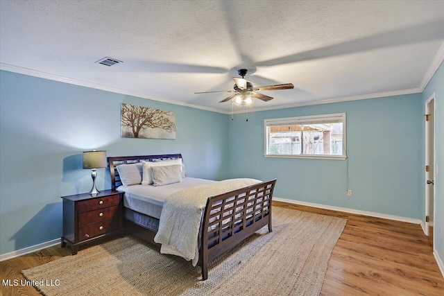 bedroom with a textured ceiling, wood finished floors, visible vents, baseboards, and crown molding