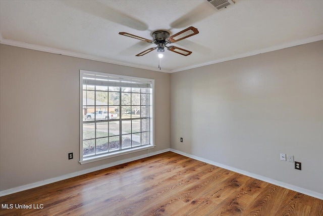 unfurnished room featuring ornamental molding, wood finished floors, visible vents, and baseboards