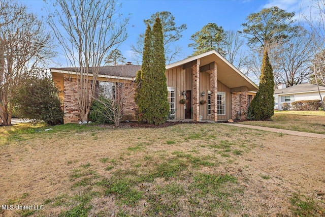 mid-century home featuring brick siding, board and batten siding, and a front yard