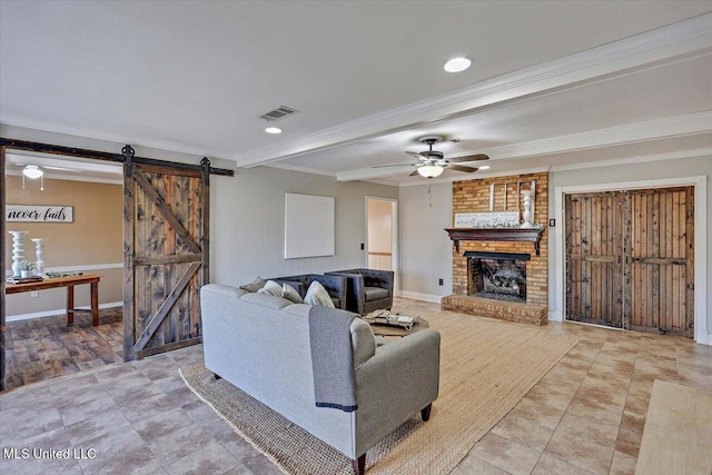 living room with a barn door, a ceiling fan, ornamental molding, a brick fireplace, and beamed ceiling