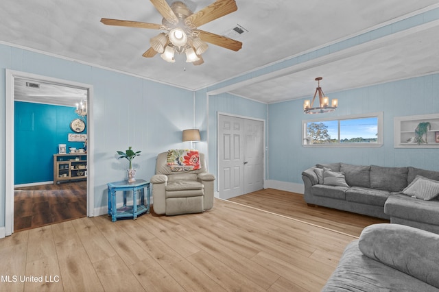 living room featuring hardwood / wood-style floors, ceiling fan with notable chandelier, and ornamental molding