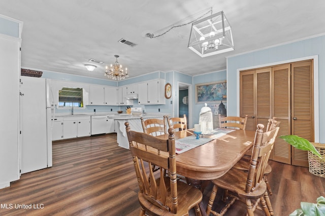 dining space featuring a notable chandelier, dark hardwood / wood-style flooring, sink, and crown molding