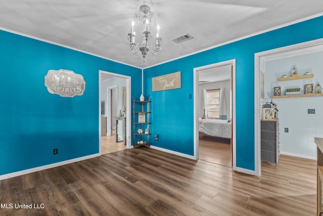 unfurnished room featuring an inviting chandelier, ornamental molding, and hardwood / wood-style flooring