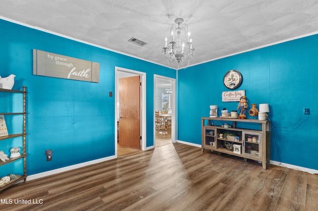 interior space with hardwood / wood-style flooring, a notable chandelier, and crown molding