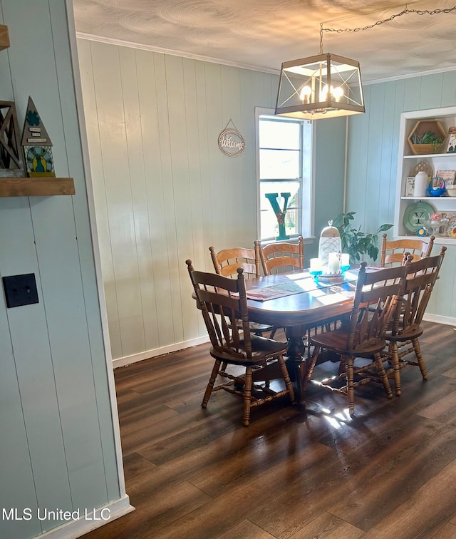 dining room with wood walls, dark hardwood / wood-style flooring, crown molding, and an inviting chandelier