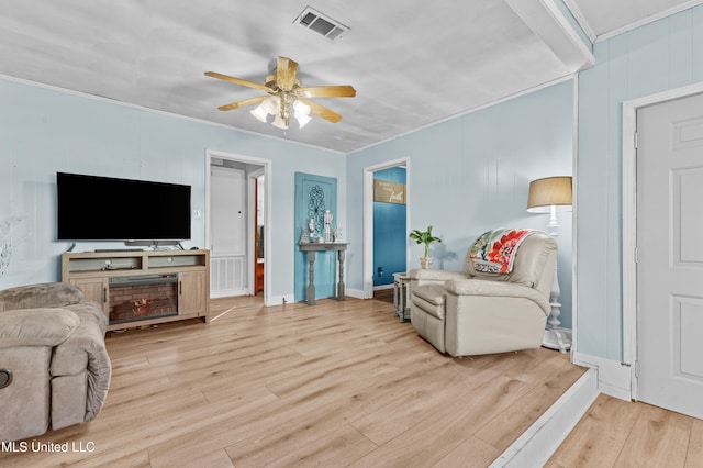 living room featuring crown molding, ceiling fan, and light wood-type flooring