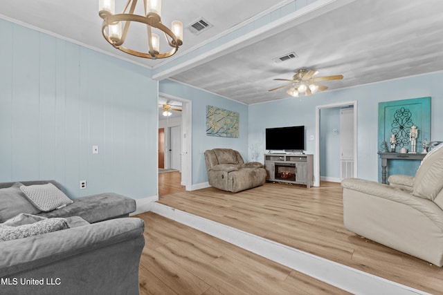 living room featuring hardwood / wood-style floors, ceiling fan with notable chandelier, a fireplace, and wooden walls