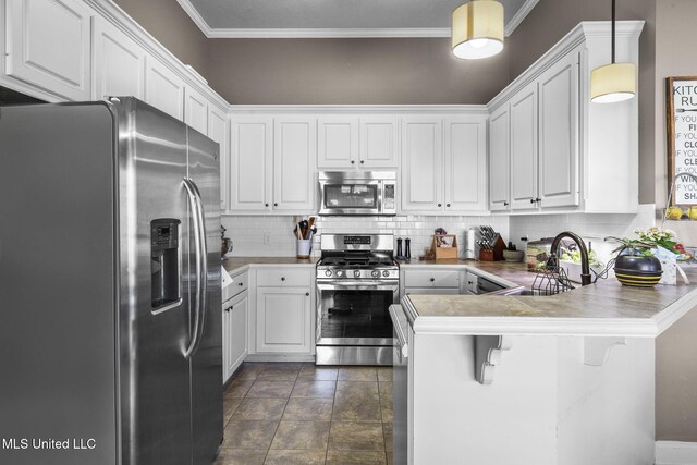 169 Beechwood Cir, Pearl, MS 39208 - kitchen featuring appliances with stainless steel finishes, a peninsula, white cabinets, tasteful backsplash, and hanging light fixtures