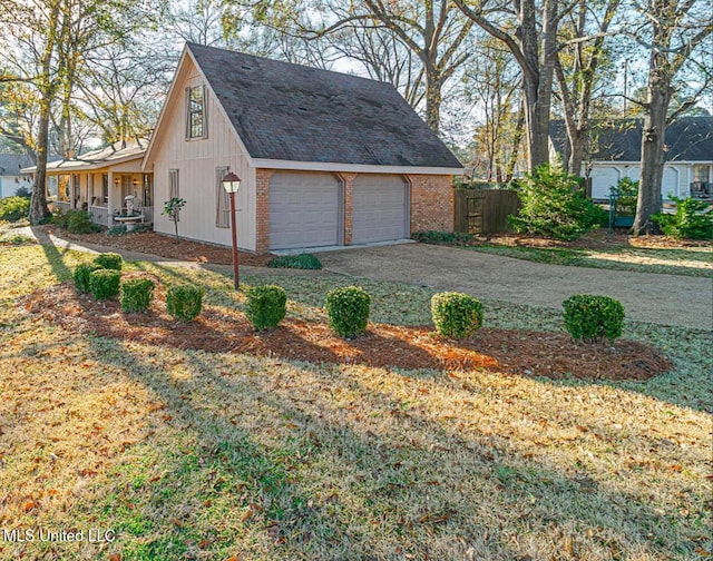 garage featuring driveway, covered porch, and fence