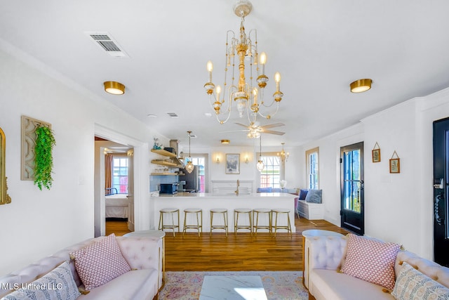 living room featuring ornamental molding, ceiling fan with notable chandelier, and light wood-type flooring