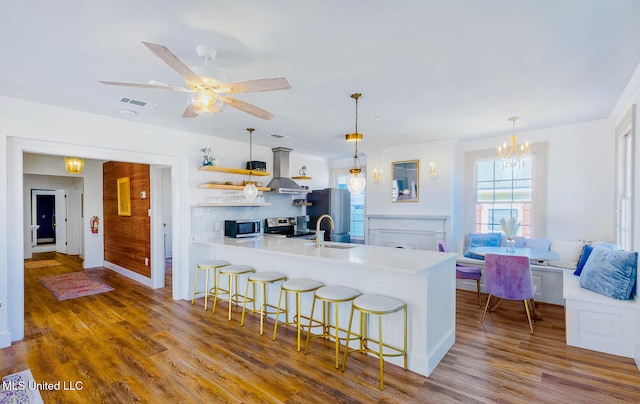 kitchen with appliances with stainless steel finishes, sink, pendant lighting, hardwood / wood-style floors, and a breakfast bar area