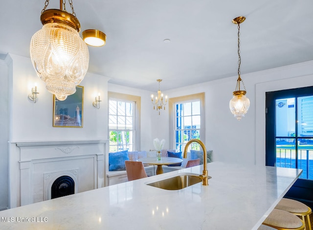 kitchen featuring pendant lighting, a notable chandelier, crown molding, and sink