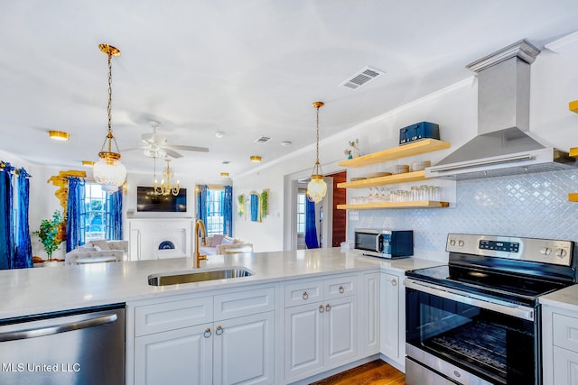 kitchen with wall chimney range hood, appliances with stainless steel finishes, white cabinets, and sink