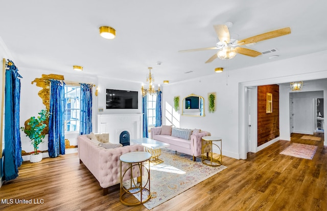 living room featuring hardwood / wood-style floors, a healthy amount of sunlight, ceiling fan with notable chandelier, and ornamental molding