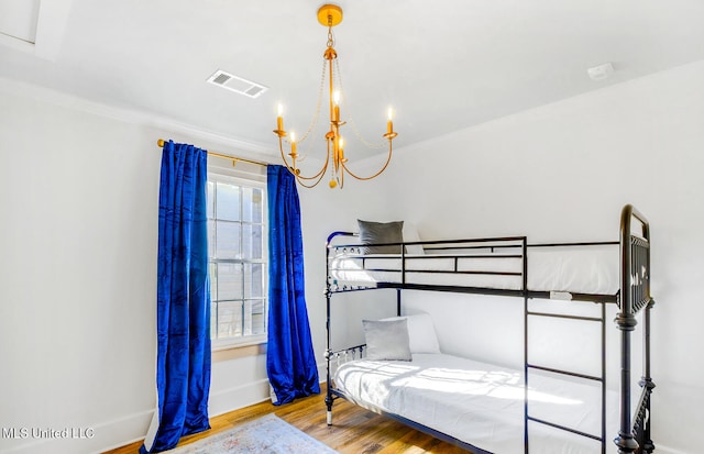 bedroom featuring an inviting chandelier, light hardwood / wood-style floors, and ornamental molding