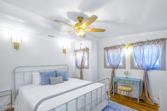 bedroom with hardwood / wood-style flooring, ceiling fan, and multiple windows