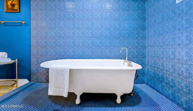 bathroom with tile patterned floors, a bathtub, and tile walls