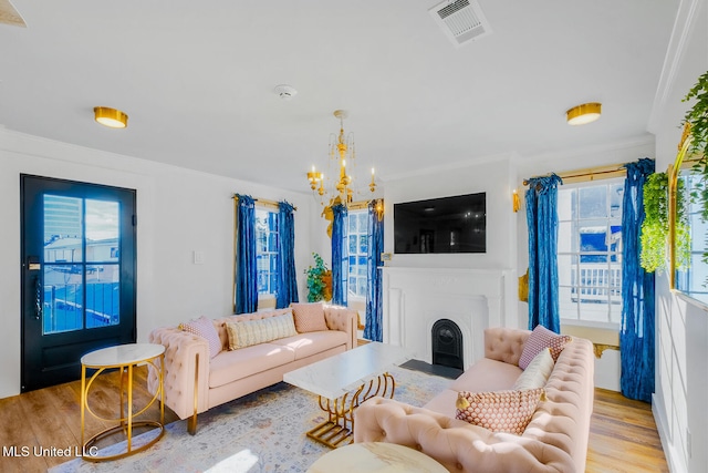 living room with light hardwood / wood-style flooring, a notable chandelier, and ornamental molding