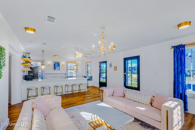 living room with hardwood / wood-style floors, ceiling fan with notable chandelier, and ornamental molding