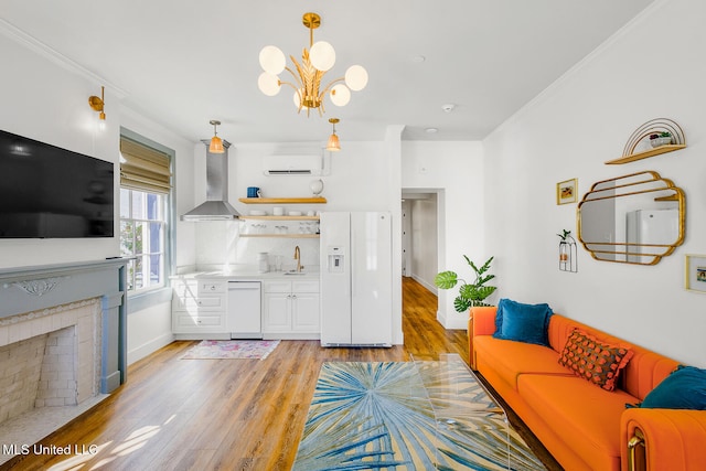 living room featuring an inviting chandelier, an AC wall unit, crown molding, and light hardwood / wood-style flooring