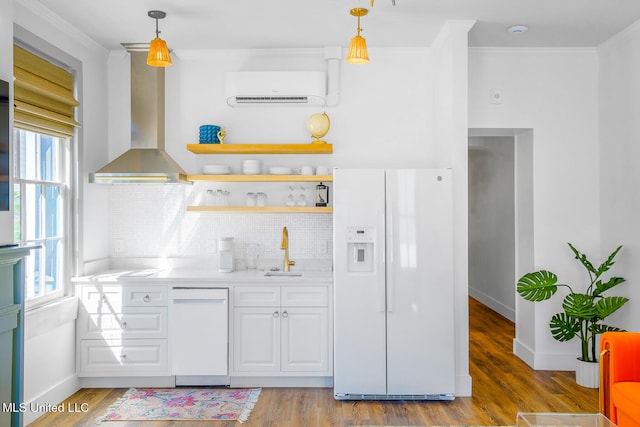 kitchen featuring a wall mounted AC, pendant lighting, white appliances, and a wealth of natural light