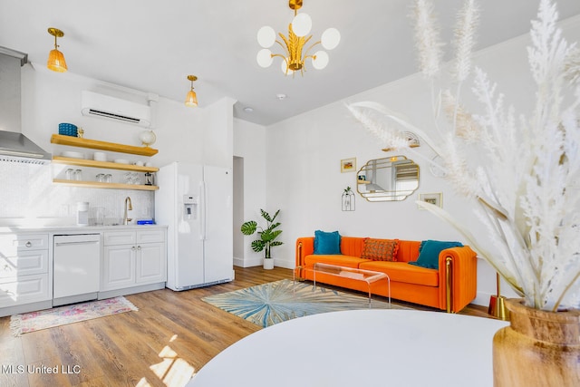 living room featuring light hardwood / wood-style floors, a wall mounted AC, a notable chandelier, and sink