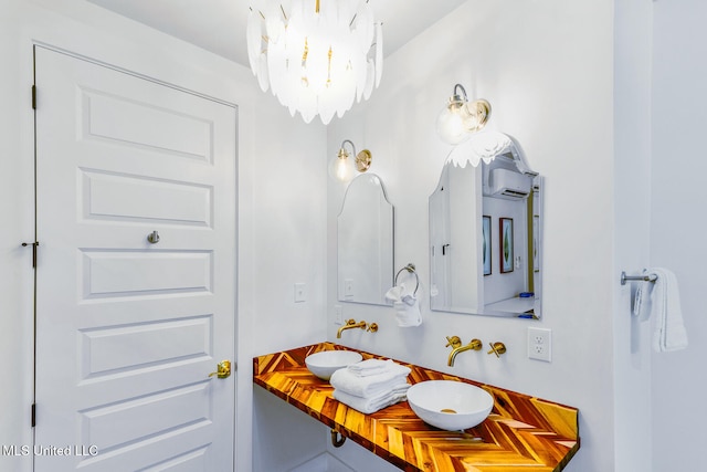 bathroom with an AC wall unit, sink, and an inviting chandelier