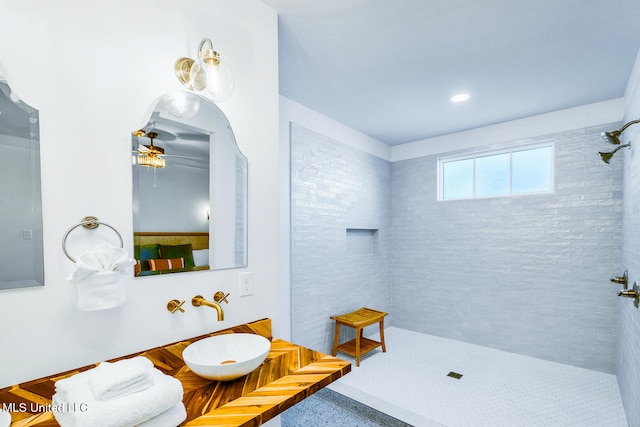 bathroom featuring a tile shower, ceiling fan, and sink