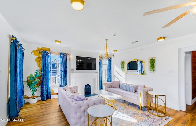 living room with crown molding, plenty of natural light, an inviting chandelier, and light hardwood / wood-style flooring