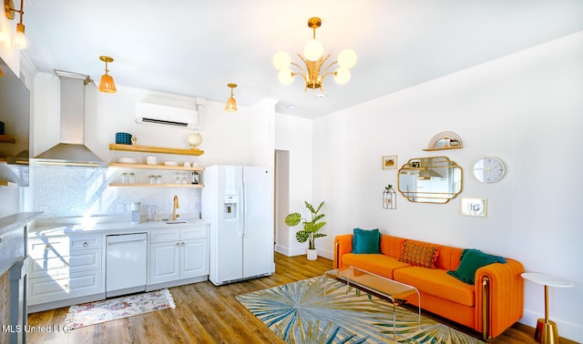 living room with a chandelier, an AC wall unit, sink, and light hardwood / wood-style flooring