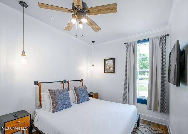 bedroom with dark hardwood / wood-style flooring, ceiling fan, and crown molding