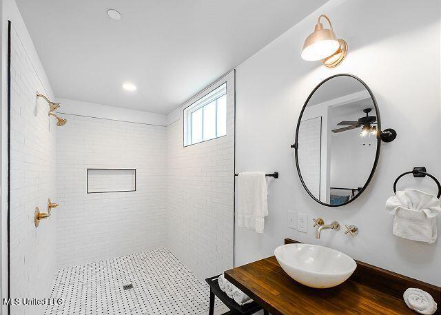 bathroom featuring a tile shower, ceiling fan, and sink