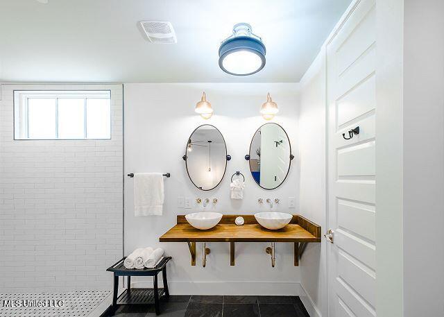 bathroom featuring tile patterned flooring, tiled shower, and sink