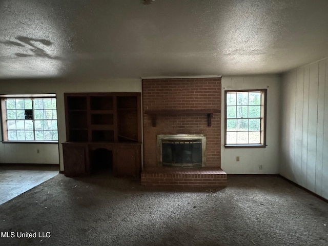 unfurnished living room featuring wood walls, a textured ceiling, a fireplace, and carpet floors