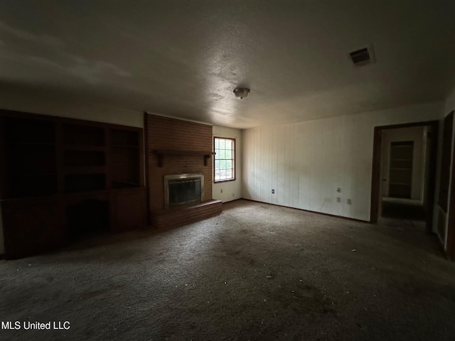 unfurnished living room featuring a textured ceiling, a brick fireplace, and dark colored carpet