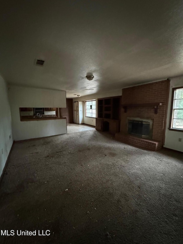 unfurnished living room with carpet and a brick fireplace