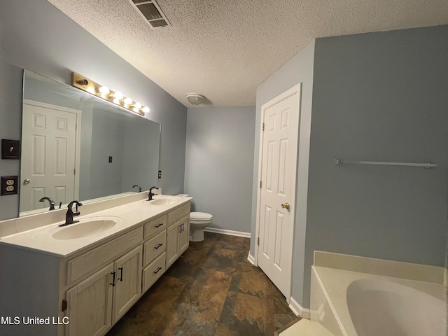 bathroom with a tub, vanity, a textured ceiling, and toilet