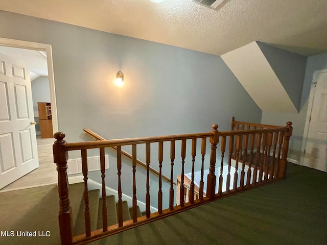 staircase with carpet, lofted ceiling, and a textured ceiling