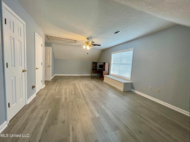 unfurnished living room with a textured ceiling, ceiling fan, light hardwood / wood-style floors, and lofted ceiling